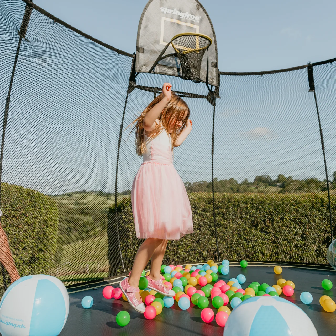 Mädchen unter dem Basketballkorb am Springfree O77 Medium Oval Trampolin.
