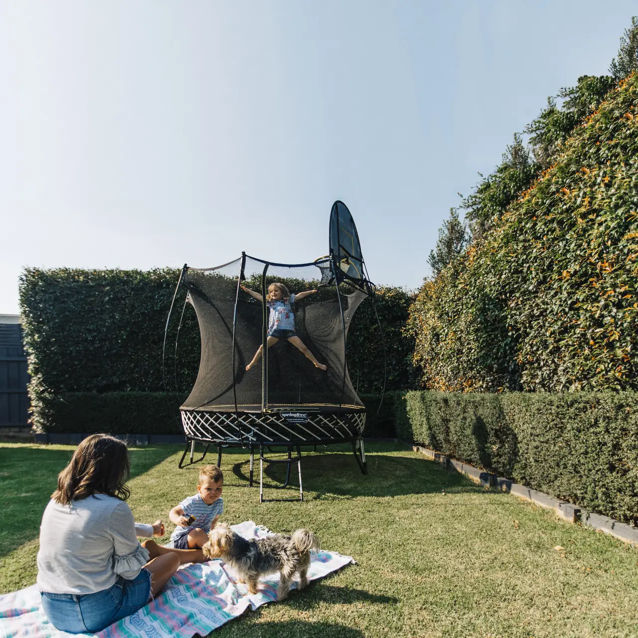 Familie beim Springfree R54 Compact Round Trampolin im Garten.