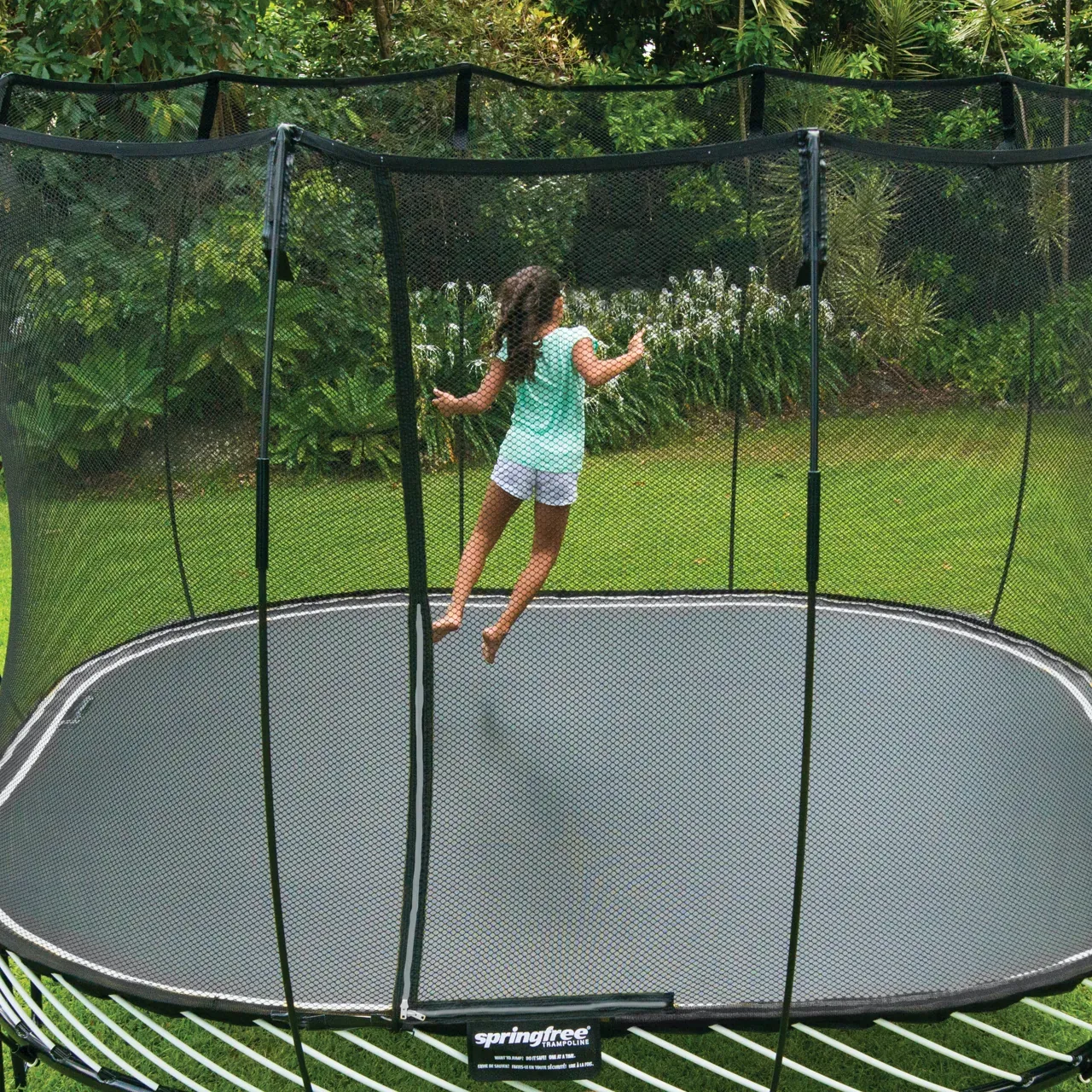 Mädchen auf dem Springfree S113 Large Square Trampolin im Garten.