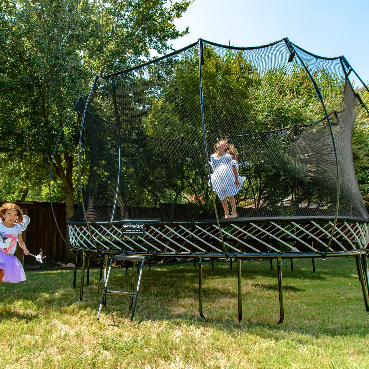 Kinder beim Springfree O92 Large Oval Trampolin im Garten.